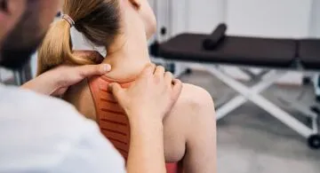 Physiotherapist hand massaging womans painful neck in physic room closeup back view. Male masseur making recovery therapy after sport injury in rehabilitation center. Chiropractic healthcare