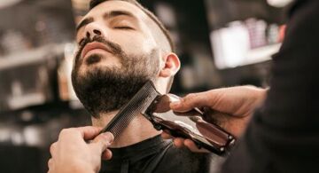 Man getting his beard trimmed with electric razor at hairdesser
